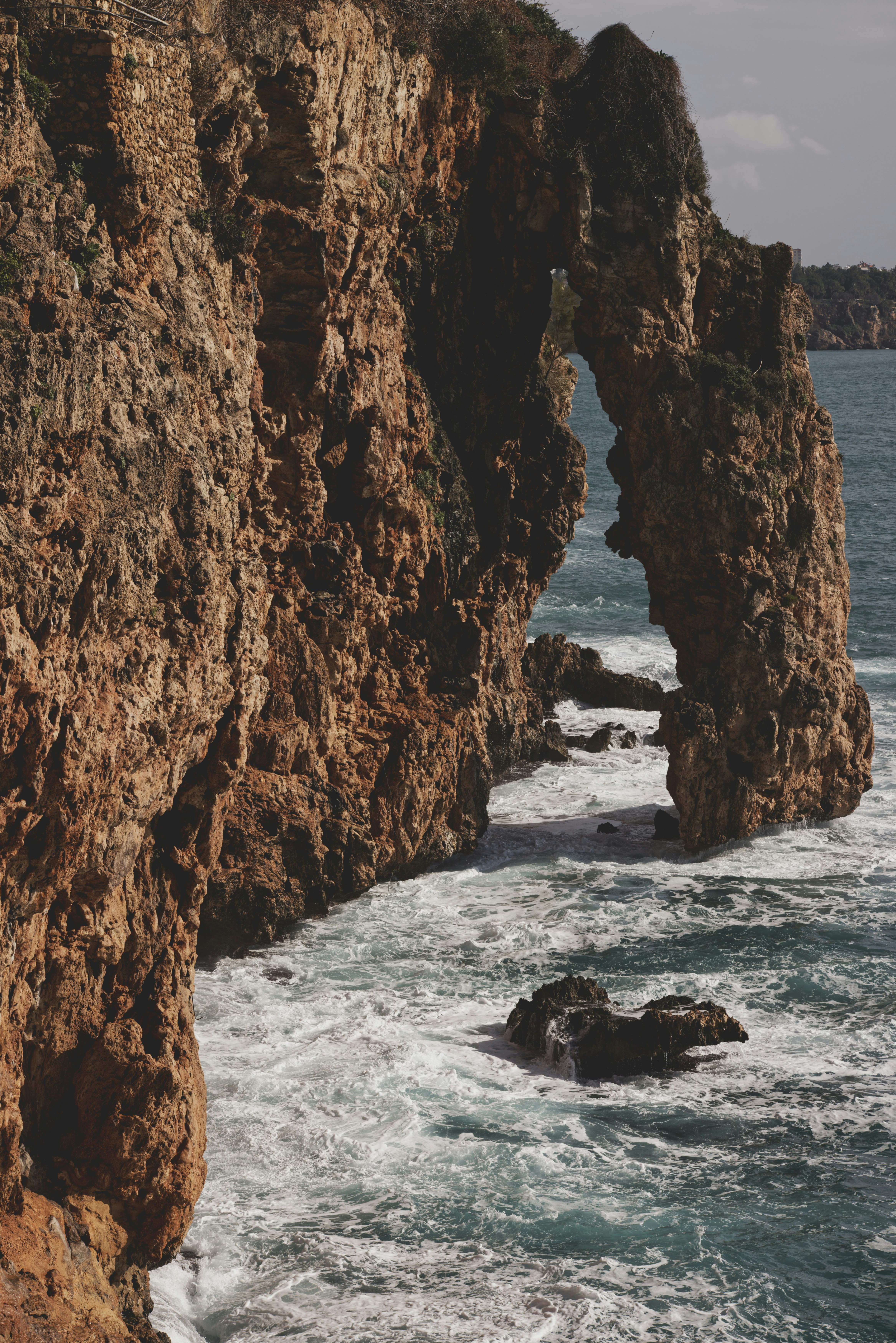 brown rock formation on body of water during daytime